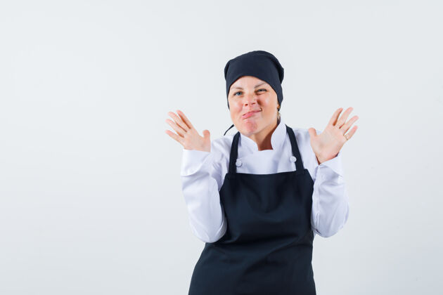 可爱一位金发女郎双手举着停车标志 身穿黑色厨师制服 表情迷人正视图肖像成人健康