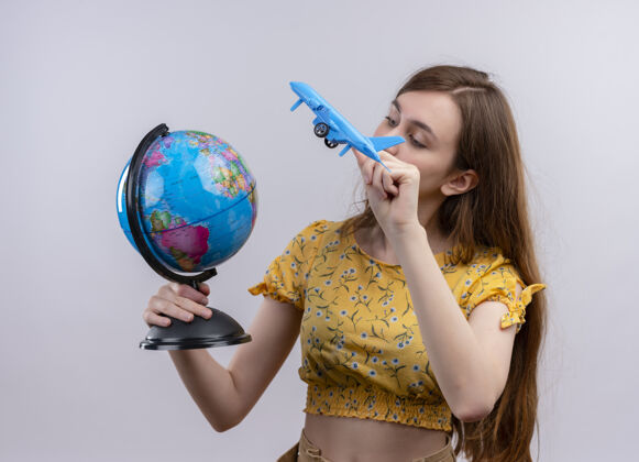 飞机年轻女孩拿着地球仪和飞机模型 看着孤零零的白墙上的地球仪模特女人女孩