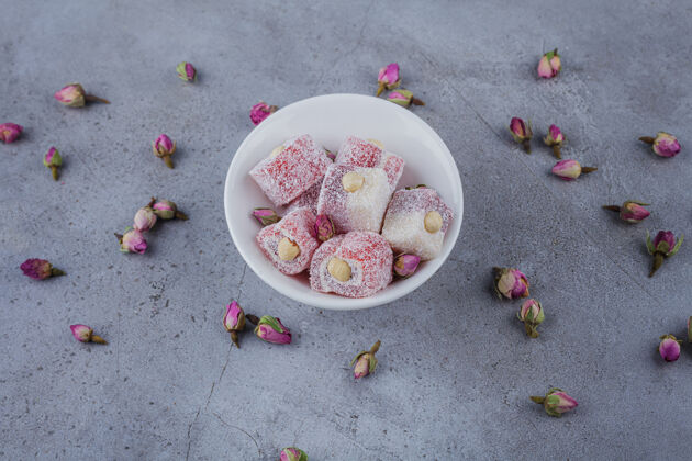 鲜花一碗白色的玫瑰和石头上的坚果糖果立方体烹饪