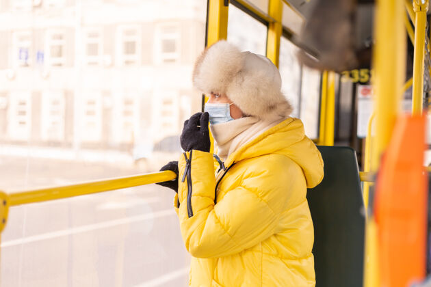 衣服一个穿着暖和衣服的年轻女子在一个冬天的城市公共汽车上的明亮的阳光肖像街道城市公共汽车站