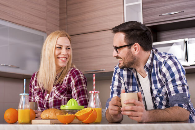 家庭一对幸福的夫妇在厨房里享用着鲜榨橙汁的早餐厨房早餐餐