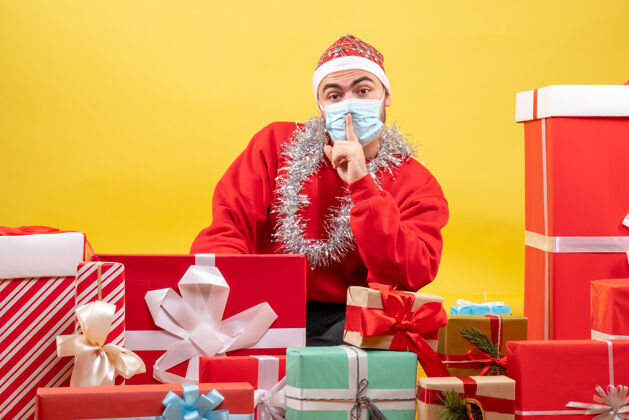 庆典正面图：年轻男性围坐在黄色的面具上展示礼物礼物圣诞节流行病