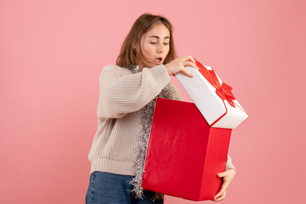 盒子年轻的女性拿着粉红色的圣诞礼物盒女士持有年轻女性