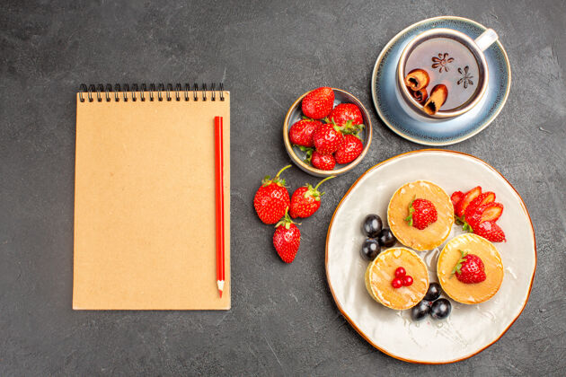 托盘顶视图小美味的水果煎饼和一杯茶的灰色地板馅饼蛋糕水果水果早餐茶