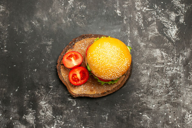 快餐俯视图黑色表面蔬菜肉汉堡面包快餐三明治面包新鲜橘子