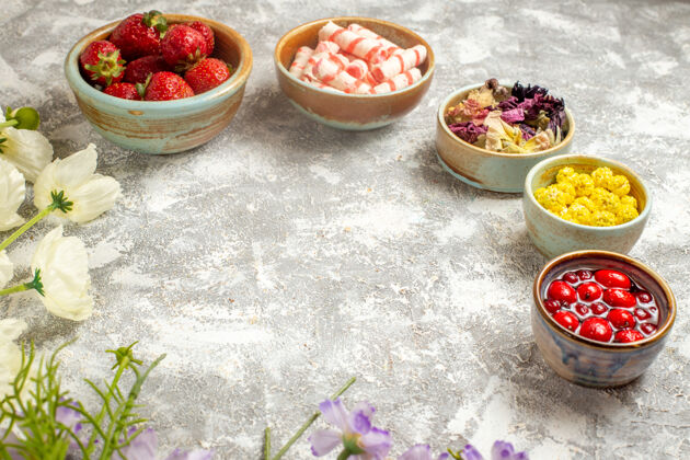 美味正面是新鲜的红色草莓 白色表面有糖果果冻花食物正面餐桌
