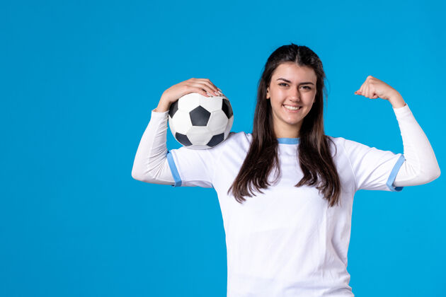 球前视图：蓝色墙上有足球的年轻女性球员蓝色视野