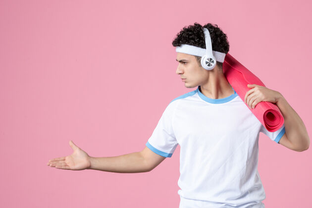 展示正面图穿着运动服的年轻男性 粉色墙上有瑜伽垫垫子运动粉色