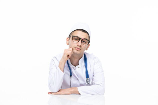 耳机正面图：年轻的医生穿着医疗服坐在桌子后面坐微笑前台