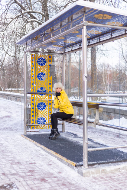 等待在寒冷的日子里 一个穿着冬衣的女人在公共汽车站等公共汽车车站年轻车站