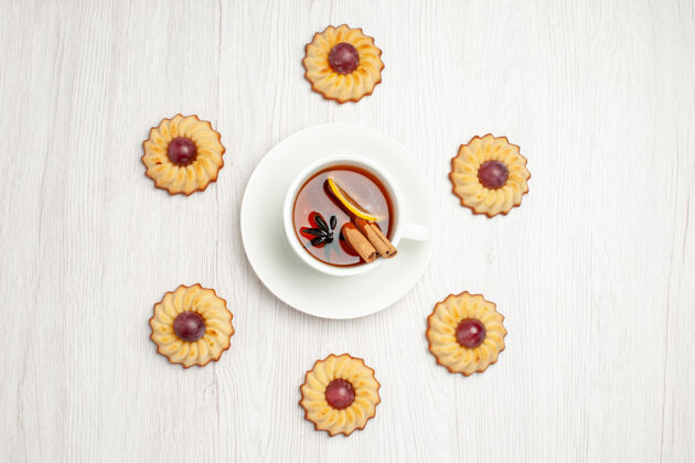 杯子俯瞰美味的葡萄饼干和一杯茶放在一张白色的桌子上甜甜的饼干派花顶部派