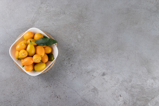 自然金橘水果放在碗里 放在大理石桌上顶视图叶子金橘