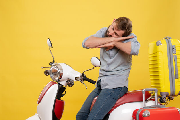 年轻人旅游概念与年轻的昏昏欲睡胡须男子坐在摩托车上它的黄色摩托车旅游输送机