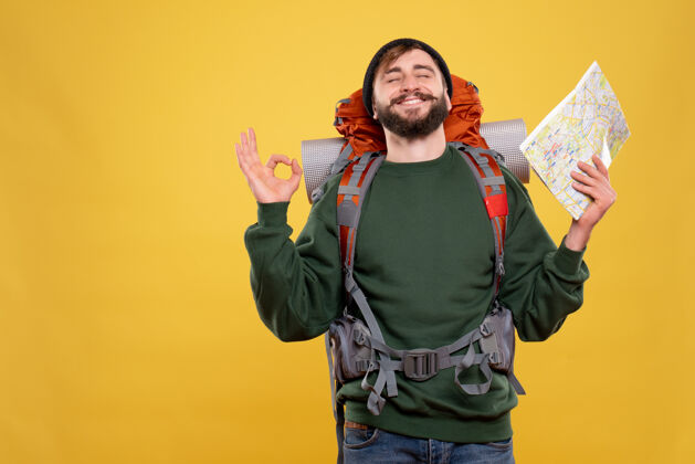 脸带着微笑的年轻人 背着背包 拿着地图 梦想着黄色的旅行理念肖像可爱漂亮
