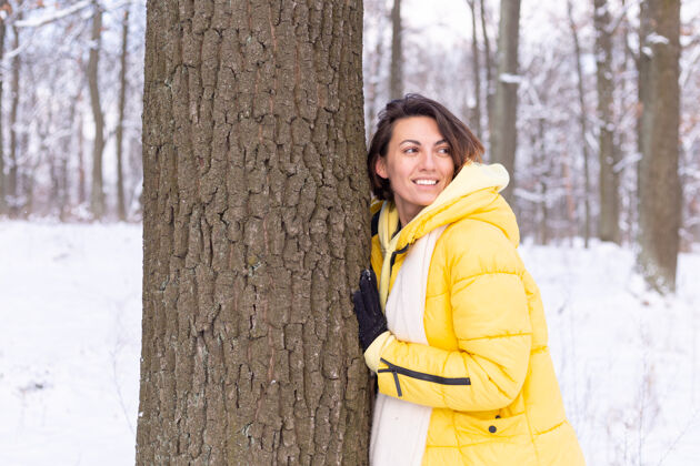 休闲美丽的年轻女子在冬天的森林里表现出对大自然的柔情 表现出对树的爱环境快乐成人