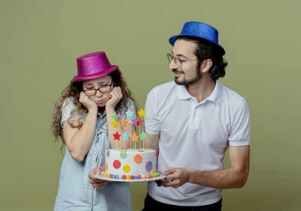 男孩小两口戴着粉蓝相间的帽子 高兴的家伙把生日蛋糕送给了被隔离在橄榄绿上的伤心女孩年轻请蛋糕