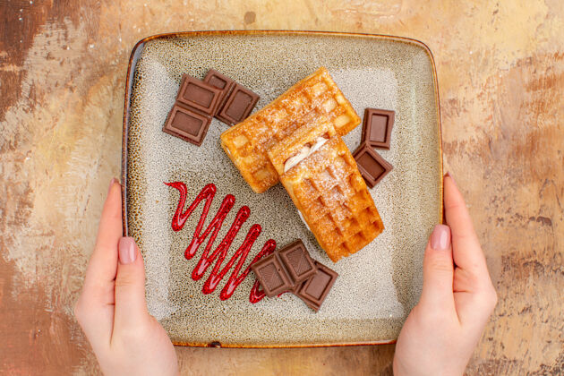 包装俯瞰美味的华夫饼与巧克力条在棕色的背景巧克力甜点手
