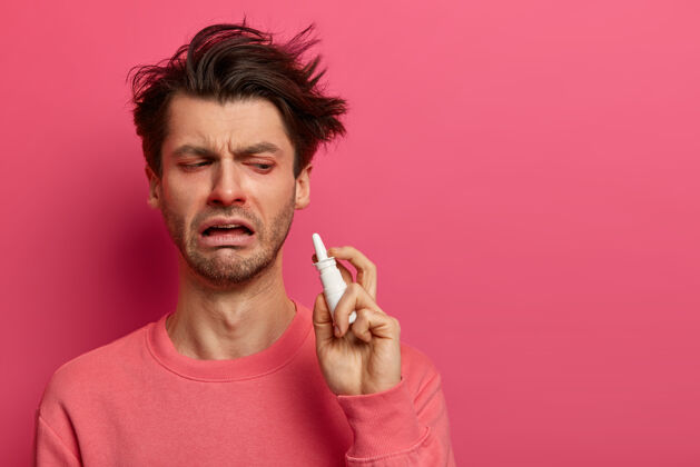 鼻子疲倦的病人有感冒的症状 拿着鼻喷雾剂 想尽快恢复 用有效的药物 滴鼻 越来越糟 隔离在粉红色的墙壁上 感觉不好治疗流感使用流行持有