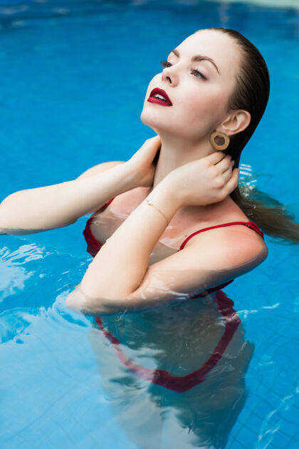 护理穿着红色比基尼的美丽年轻女子在夏日游泳池里令人耳目一新刷新边缘休闲