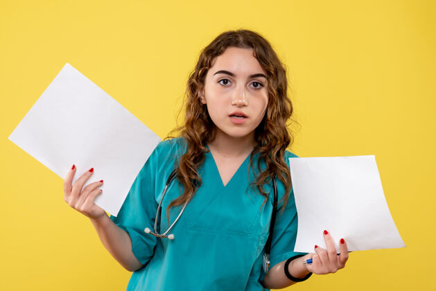女性正面图女医生穿着医用衬衫手持纸片分析 大流行性健康病毒covid-19制服情绪黄色妇女纸张