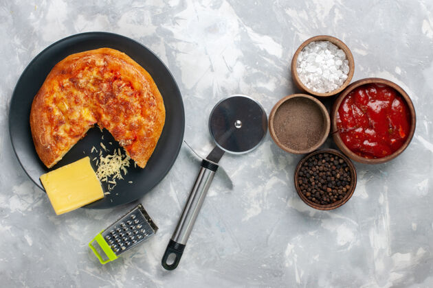 饮食在白色的桌子上俯瞰不同调味料的烤比萨饼健康食物传统