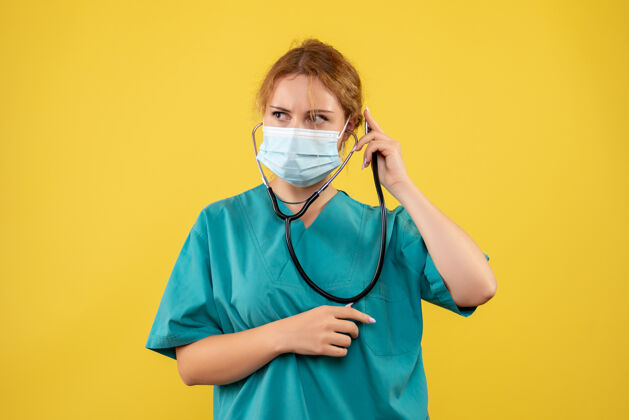 健康黄色墙上穿着医疗服 戴着听诊器面罩的女医生的正视图人医疗器械