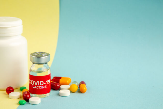 科学黄蓝色背景上不同药丸的抗covid疫苗的前视图视图瓶子药丸