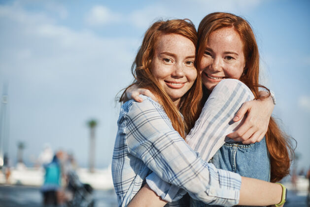 休闲两位红发雀斑的美丽女性朋友的可爱照片 在街上拥抱 笑容满面 表达关心和爱生活方式和关系理念公园海滩草地
