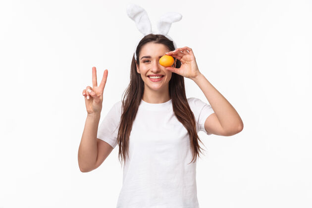 人肖像富有表现力的年轻女子戴着兔子的耳朵和鼻子 手里拿着彩蛋年轻有趣头发