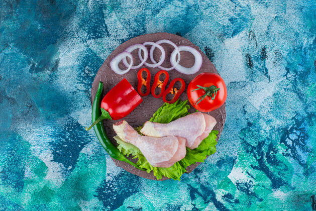 生菜胡椒 洋葱圈 西红柿 生菜和鸡腿放在一块板上 蓝色背景蛋白质胡椒环
