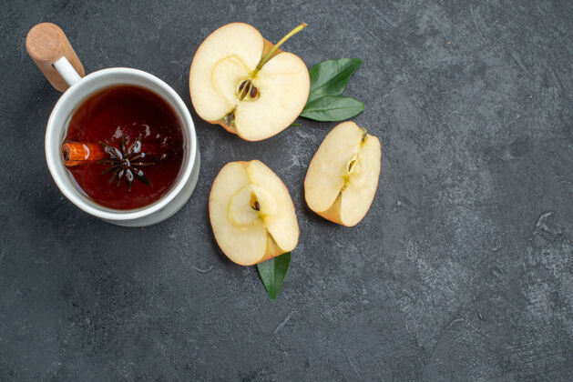 新鲜顶部特写镜头一杯茶一杯桂皮茶贴在苹果片旁边棍棒健康可食用水果