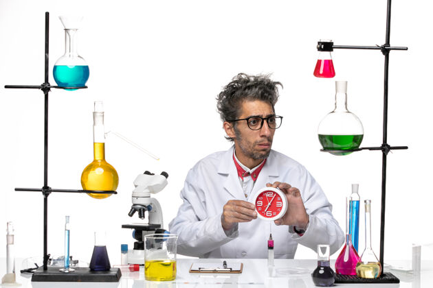 病毒正面图身穿医疗服的男科学家在白色办公桌上拿着红色的时钟化学冠状病毒-实验室病毒健康人专业比赛
