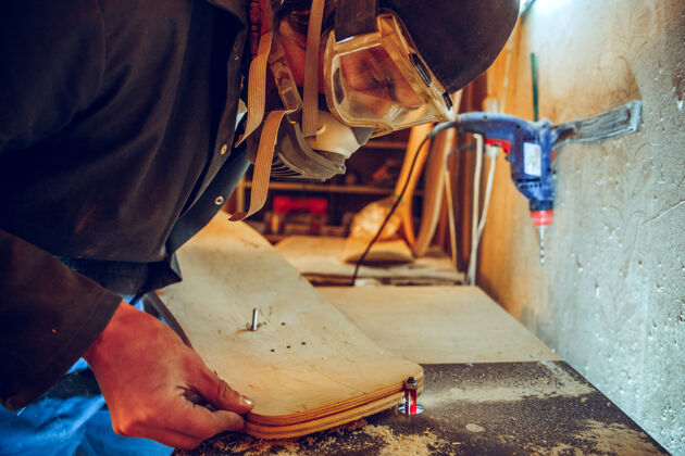 建筑英俊的木匠在车间里用木溜冰鞋工作的肖像 剖面图专业车间木工