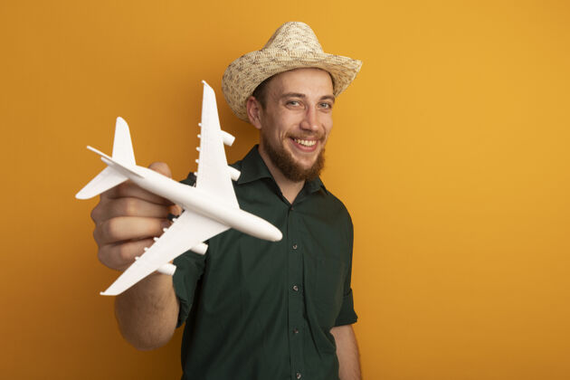 黑发微笑的金发帅哥 头戴沙滩帽 手里拿着橙色的飞机模型英俊男人金发