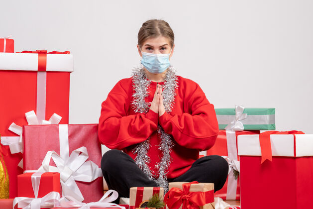 一年正面图：年轻女性戴着无菌面具坐着 手里拿着圣诞礼物年轻女性圣诞节现在