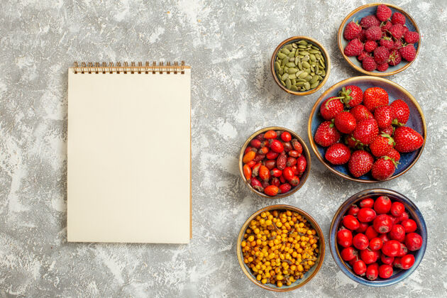 记事本顶视图新鲜草莓与记事本和浆果的白色背景成熟新鲜草莓背景
