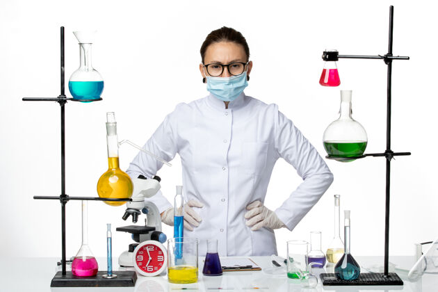 医学前视图身穿医疗服的女化学家戴着面具在白色背景上摆姿势病毒化学实验室covid-splash病毒科学姿势