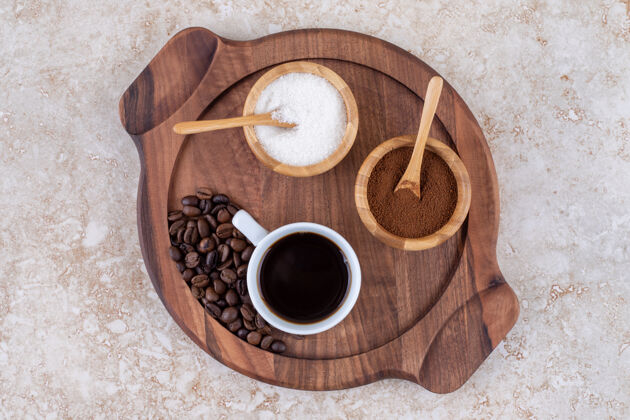 杯子咖啡和糖放在一个小木托盘上美味研磨