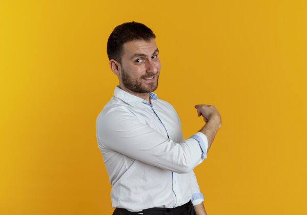 侧身自信的帅哥侧身站在橙色的墙上 指指点点商务男士背部衬衫