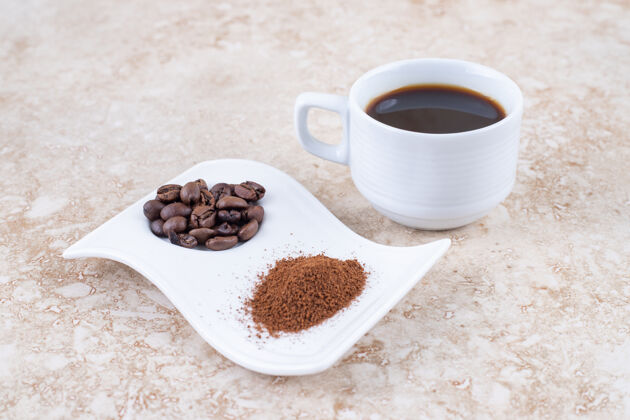 咖啡一杯煮好的咖啡 旁边放着咖啡豆和磨碎的咖啡粉 放在一个漂亮的盘子里咖啡粉芳香咖啡杯