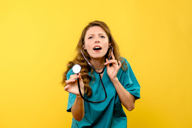 成人黄色墙上女医生使用听诊器的正面图正面微笑医疗器械