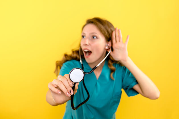 医生黄色墙上女医生使用听诊器的正面图医疗器械听诊器黄色