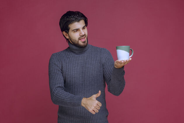 员工一个穿着灰色毛衣的男人手里拿着一个咖啡杯男性年轻聪明