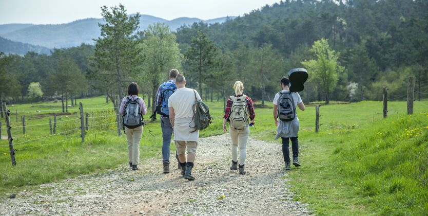 风景背着背包的年轻朋友在森林里散步 享受美好夏日的背影散步天空白天