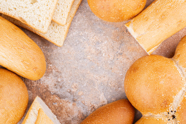 美味不同的切片面包和全面包 在大理石背景上顶视图美味面包