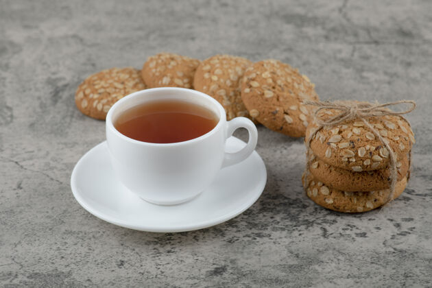 美味一堆美味的燕麦片饼干和一杯茶放在大理石表面膳食谷类茶
