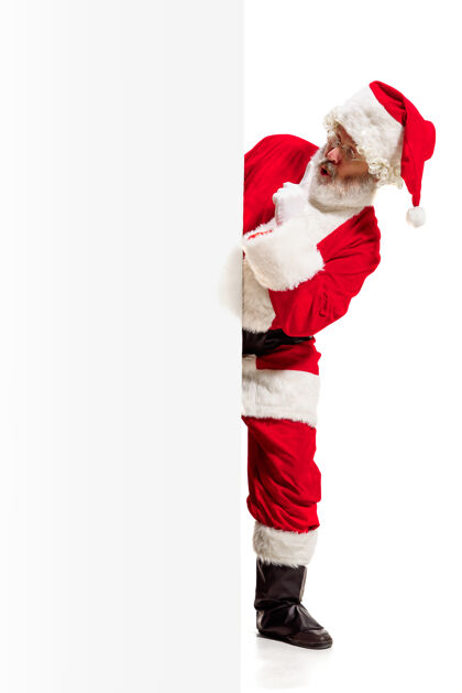 白色快乐惊喜的圣诞老人指着空白的广告横幅背景和复制空间微笑的老人在白色空白的空白海报显示举行年服装