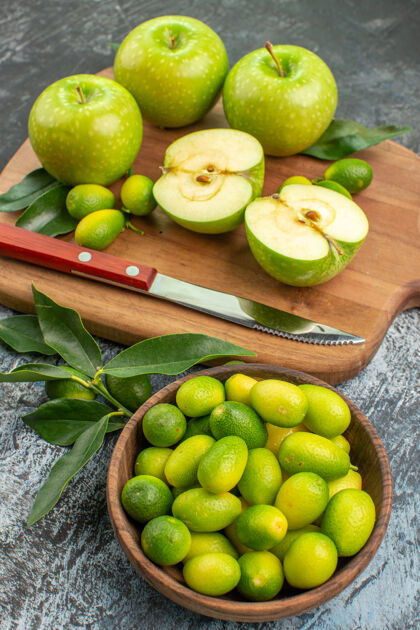 碗侧视图水果青苹果和切菜板上的一碗柑橘类水果刀绿色苹果董事会