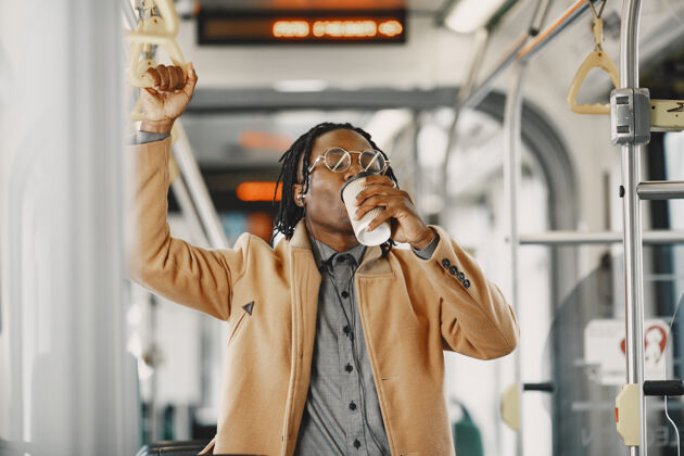 黑人一个非洲裔美国人坐在城市巴士上一个穿棕色外套的人一个喝咖啡的人公众非洲黑人
