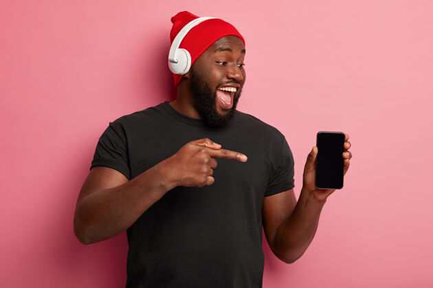 音频人 科技 生活方式和广告理念快乐的黑皮肤男人展示智能手机设备的空白屏幕耳机手机指向